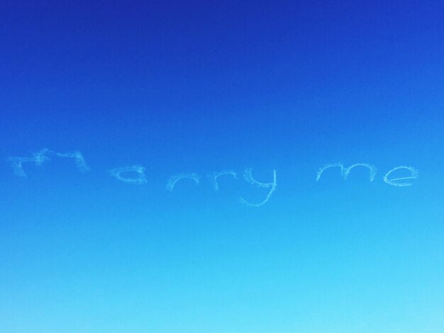 Foto vista de ángulo bajo de casarme texto por senderos de vapor en el cielo azul claro