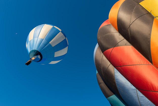 Foto vista de bajo ángulo de coloridos globos de aire caliente volando contra un cielo azul claro