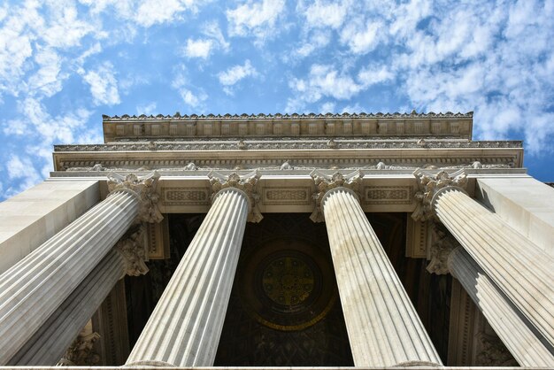 Foto vista en bajo ángulo de columnas arquitectónicas históricas contra un cielo nublado