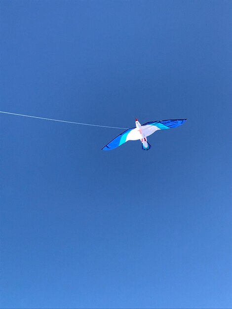 Foto vista de ángulo bajo de una cometa volando contra un cielo azul claro