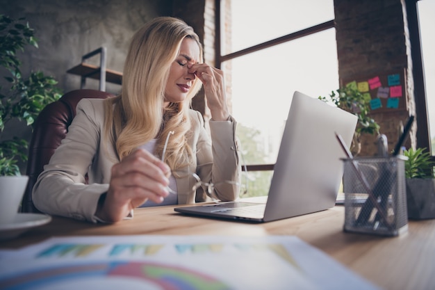 Vista de ángulo bajo por debajo de la hermosa mujer que sufre de dolor de cabeza en su lugar de trabajo que necesita descansar un poco