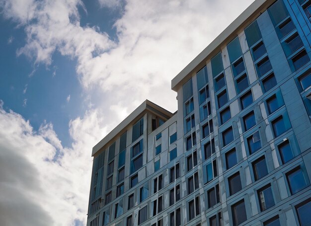 Vista de bajo ángulo de un edificio de gran altura con ventanas azules y cielo nublado y luz solar generativa ai