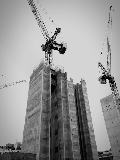 Vista de ángulo bajo de edificios en construcción y grúa contra un cielo despejado