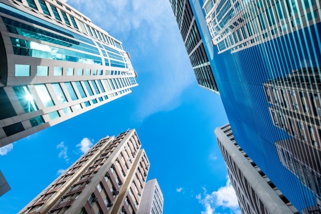 Vista de ángulo bajo de edificios de rascacielos con ventanas de vidrio y cielo azul