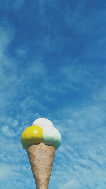 Foto vista en bajo ángulo de la escultura del cono de helado contra el cielo nublado