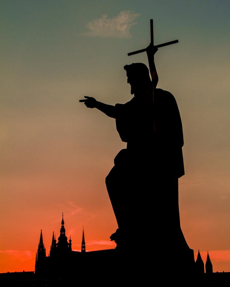 Foto vista en bajo ángulo de la escultura de silueta con cruz contra el cielo nublado