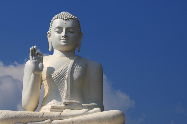 Vista de ángulo bajo de la estatua blanca de Buda contra el cielo azul en un día soleado