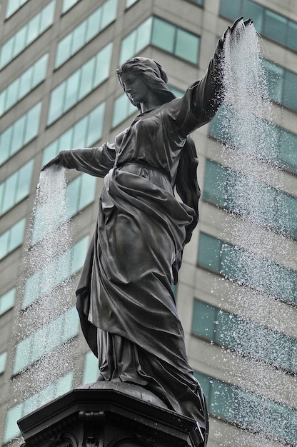 Foto vista de bajo ángulo de la estatua contra los edificios de la ciudad