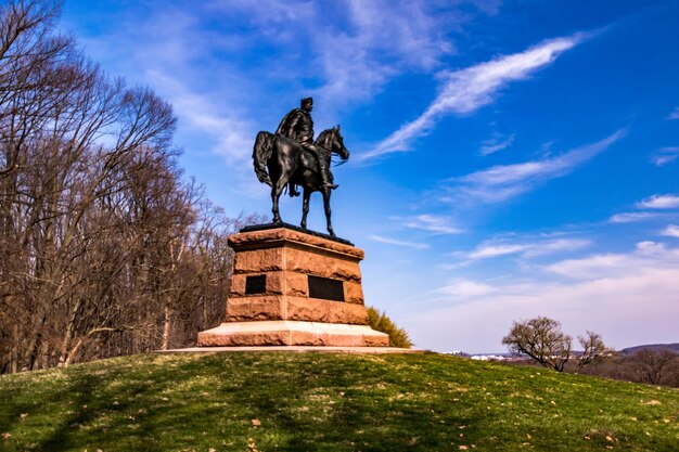 Vista de ángulo bajo de la estatua humana y animal negra contra el cielo azul en el parque nacional de Valley Forge