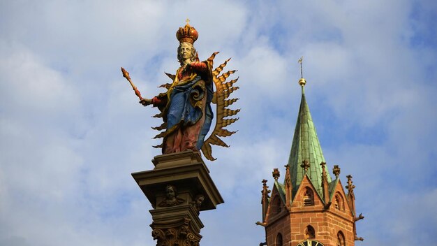 Vista de bajo ángulo de la estatua y la iglesia contra un cielo nublado