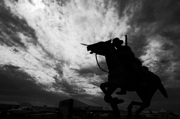 Vista de ángulo bajo de la estatua silueta contra el cielo nublado