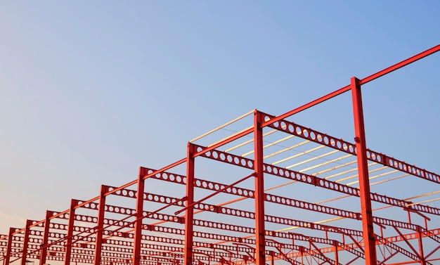 Vista de ángulo bajo de la estructura de viga almenada de metal rojo del edificio industrial en el sitio de construcción