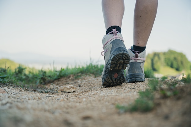 Vista de ángulo bajo de excursionista mujer con zapatos de senderismo de pie en la acera durante un viaje activo.