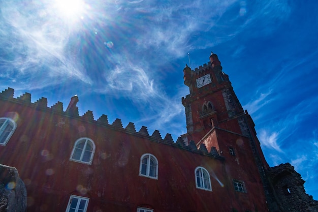 Vista en bajo ángulo de la fachada roja que muestra la silueta del Palacio Pena con la torre del reloj