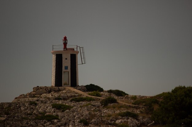 Foto vista de ángulo bajo del faro en el acantilado por el edificio contra el cielo