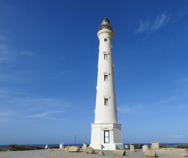 Foto vista de ángulo bajo del faro por el edificio contra el cielo azul