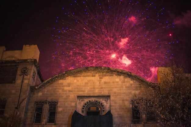 Foto vista de ángulo bajo de fuegos artificiales en el edificio contra el cielo por la noche