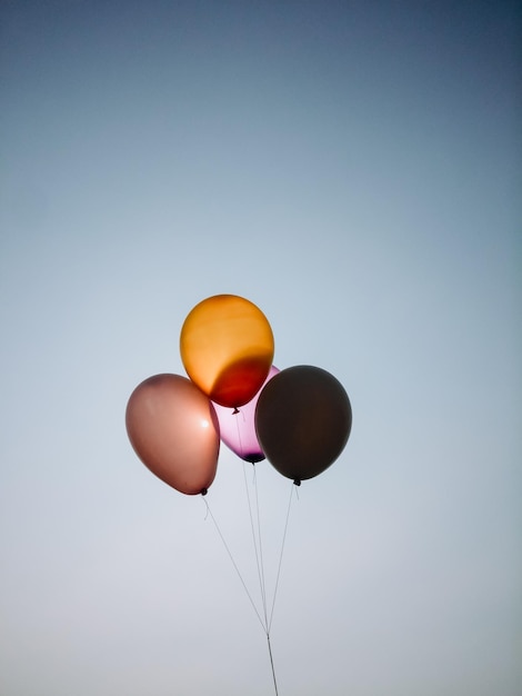 Vista de bajo ángulo de globos coloridos volando contra un cielo despejado