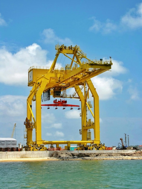 Foto vista de ángulo bajo de una grúa industrial frente al mar contra un cielo nublado