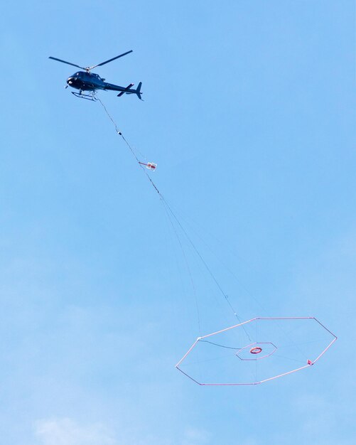 Foto vista de bajo ángulo de un helicóptero que transporta equipos de juego en el cielo azul