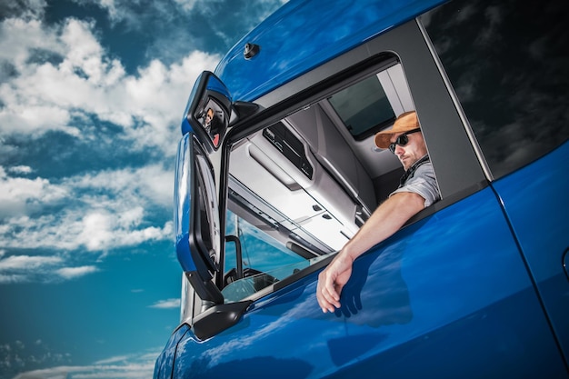 Foto vista de ángulo bajo de un hombre conduciendo un camión contra el cielo azul