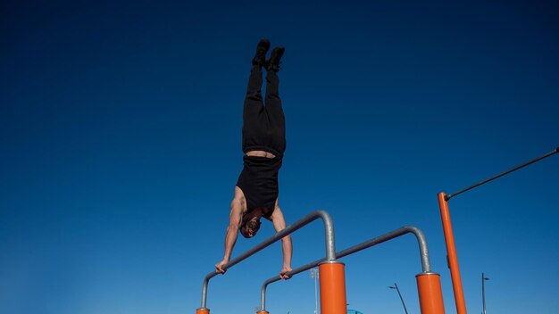 Foto vista de ángulo bajo de un hombre escalando una cuerda contra un cielo azul claro