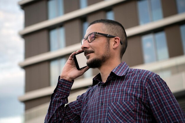 Foto vista de ángulo bajo de un hombre hablando por teléfono inteligente contra edificios