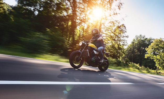 Vista de bajo ángulo de un hombre montando una motocicleta en la carretera contra los árboles