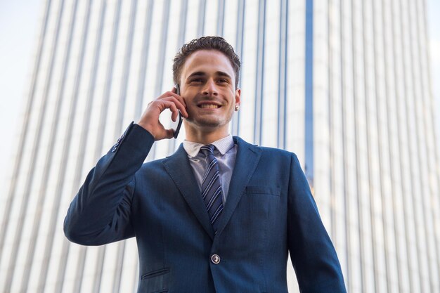 Vista de bajo ángulo de un hombre de negocios hablando por teléfono en la ciudad