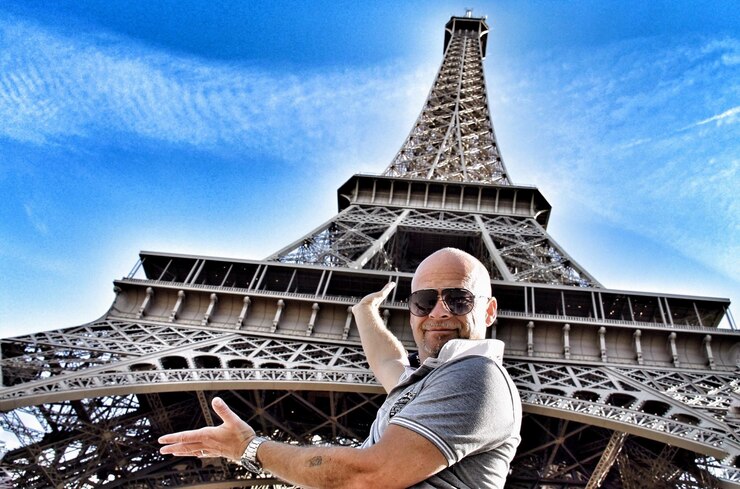 Foto vista de bajo ángulo del hombre de pie contra la torre eiffel