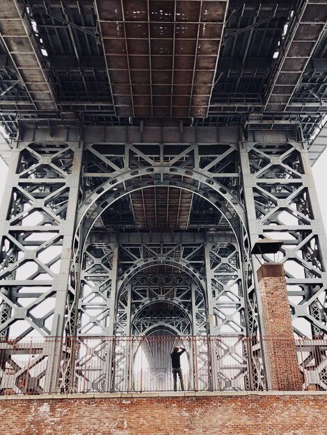 Foto vista en bajo ángulo de un hombre de pie bajo un puente