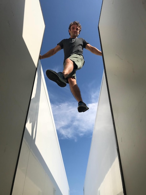 Foto vista en bajo ángulo de un hombre saltando contra el cielo