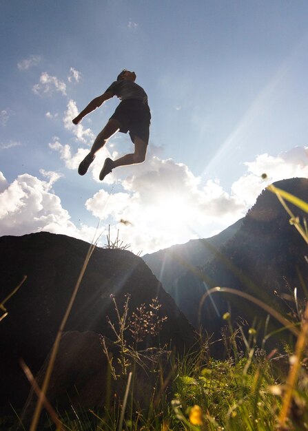 Foto vista de ángulo bajo de un hombre saltando de una montaña contra el cielo