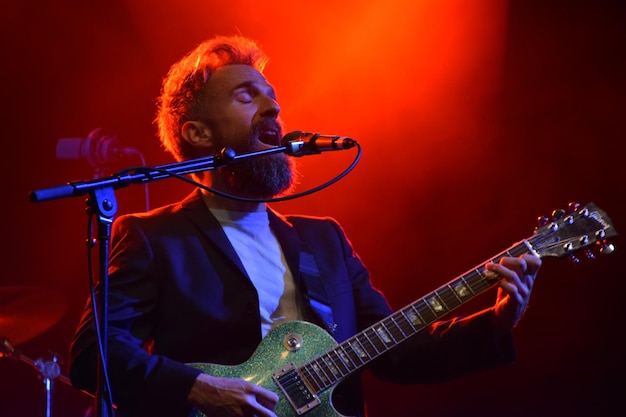 Vista de ángulo bajo de un hombre tocando la guitarra mientras canta en el escenario