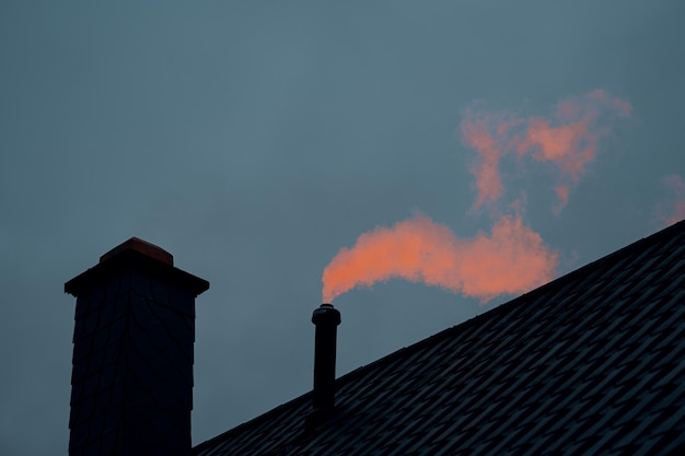 Vista de ángulo bajo del humo que emite la chimenea contra el cielo al atardecer