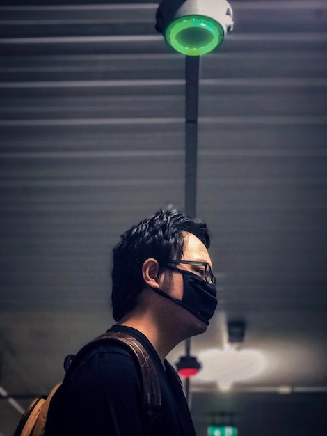 Vista de ángulo bajo de un joven contra el techo iluminado y las luces