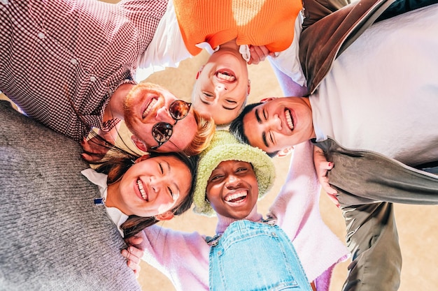 Vista de ángulo bajo de jóvenes amigos multiétnicos de pie juntos sonriendo y divirtiéndose