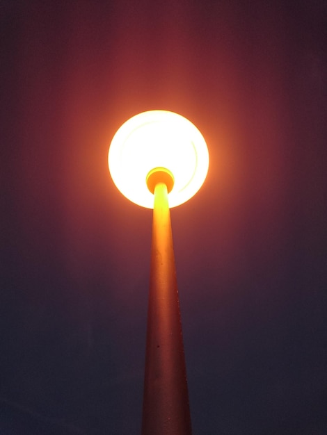 Foto vista de ángulo bajo de la lámpara iluminada contra el cielo por la noche