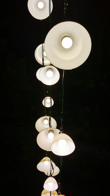 Foto vista de ángulo bajo de luces colgantes iluminadas colgando por la noche