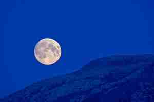 Foto vista de bajo ángulo de la luna contra las montañas por la noche