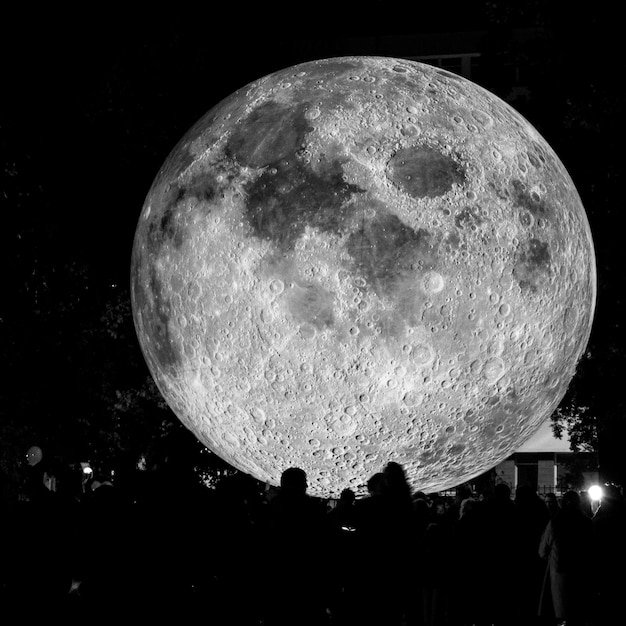 Foto vista de ángulo bajo de la luna iluminada contra el cielo por la noche