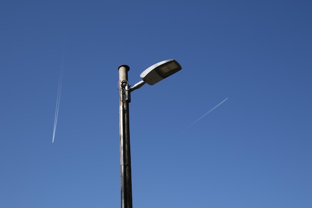 Vista de bajo ángulo de la luz de la calle con rastros de vapor en el cielo azul