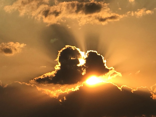 Vista de ángulo bajo de la luz solar que fluye a través de las nubes durante la puesta de sol