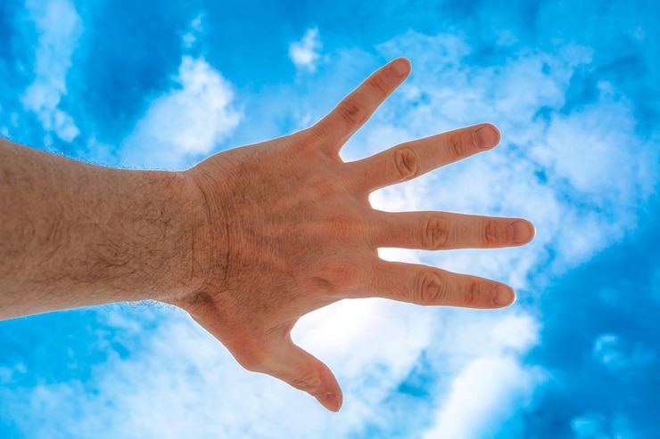 Foto vista de ángulo bajo de la mano humana contra el cielo azul