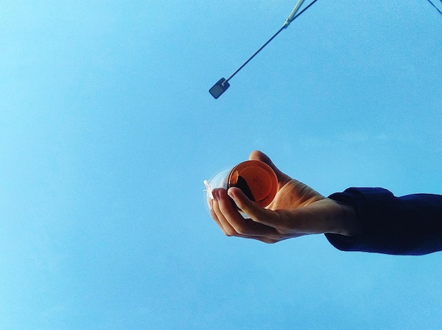 Foto vista de ángulo bajo de la mano de la persona contra el cielo azul