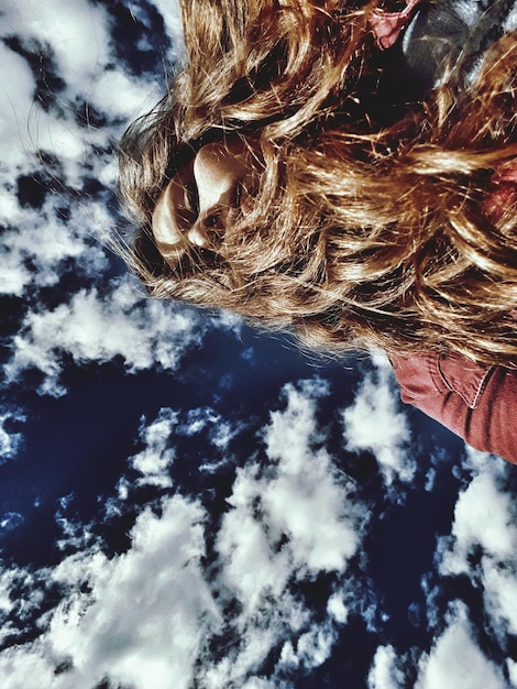 Foto vista de bajo ángulo de una mujer con cabello largo contra un cielo nublado