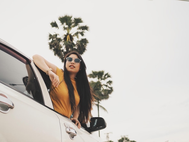 Foto vista de ángulo bajo de una mujer en un coche contra un cielo despejado