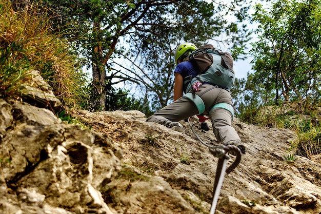 Vista de ángulo bajo de una mujer escalando un acantilado