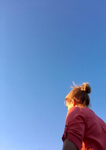 Foto vista de bajo ángulo de una mujer de pie contra un cielo azul claro