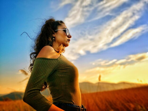 Vista de bajo ángulo de una mujer de pie contra el cielo durante la puesta de sol